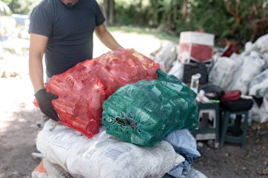 Yakından bakınca, kimliği belirsiz yetişkin bir İspanyol adamın elleri geri dönüşümlü kristal şişeleri tartarken görülüyor.