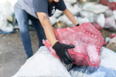 İspanyol işçilerin elleri, geri dönüşüme ve sürdürülebilir çabalara katkı sağlayarak geri dönüşümlü cam şişeleri çuval yığınının üzerine yığıyor.