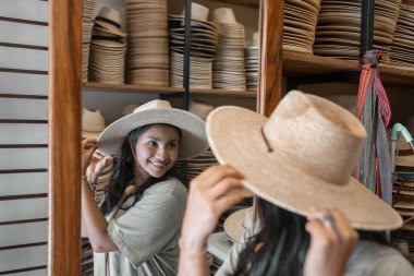 Genç bir İspanyol kadın aynaya bakıyor ve yeni bir şapka deniyor. Geleneksel Latin kıyafetleri kavramı