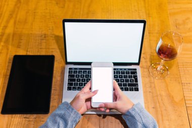 Yukarıdan gelen isimsiz bayan serbest çalışan akıllı telefondan tablet ve kırmızı şarabın yanında boş ekranla restoranda otururken