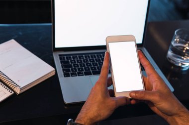 Yukarıdan gelen tanımlanamayan erkek işçi cep telefonundan gelen mesajlar boş ekran ile netbook ile masada otururken