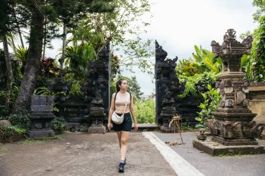 Geleneksel bir Bali girişinden geçen kadın doğal bir şekilde Hindu süslemeleriyle süslenmiş.