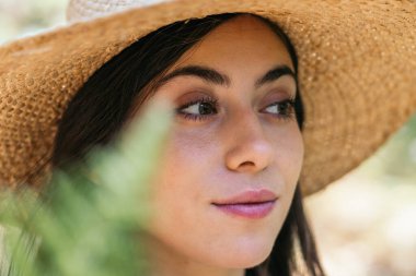 Ormandaki güzel genç bir kadının yakından çekilmiş portresi, bitkilerin yapraklarının arasından görülüyor.