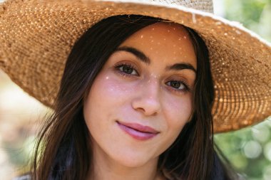 Hasır şapkalı güzel bir kadının portresi ormanda bir günün tadını çıkarıyor.