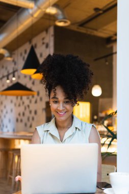 İnternette yazı yazan kıvırcık saçlı Afro-Amerikan kadın.