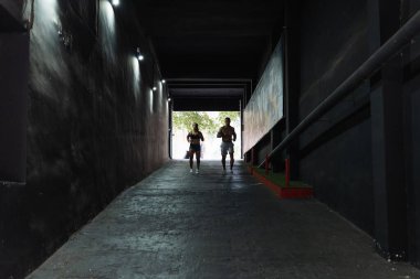 Spor giyim sektöründe, uzak mesafeden sportif bir çift sokakta eğitim görürken duvarlar arasında hızla koşuyor.