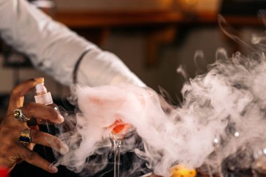 Şık siyah barmen geleneksel bir kokteyl barında kokteyl hazırlıyor.