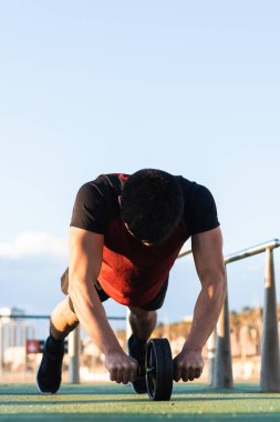 Spor sahasında yapılan yoğun antrenman sırasında karın kaslarını kas tekeriyle çalıştıran tanınmayan güçlü sporcu erkek sporcu.