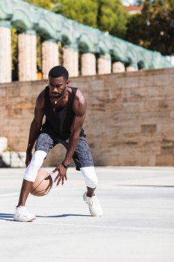 Kararlı Afrikalı Amerikalı erkek sporcu yazın sahada basketbol oynuyor.