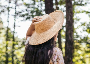 Hasır şapkalı bir kadının yakınında. Ormanda bir günün tadını çıkarıyor.