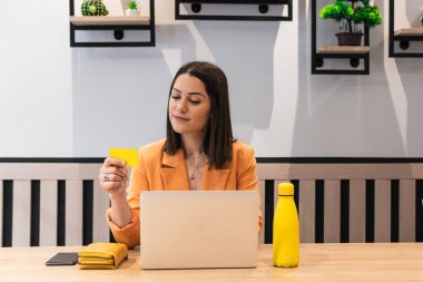 Naylon kart kullanan ve internetten alışveriş yapan neşeli bir kadın.