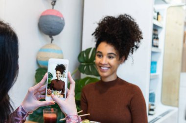 Afro-Amerikan arkadaşının restoranda dürtme kabıyla masada otururken fotoğrafını çeken tanınmamış bir kadın.