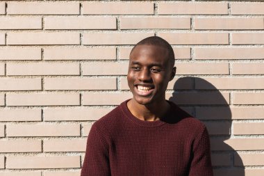 Mutlu, genç, Afro-Amerikan erkek güneş ışığının altında duruyor. Kale duvarının yanında.