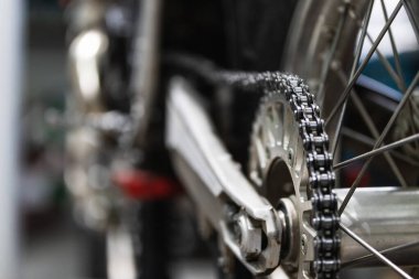 Garajda bakım sırasında krom detaylar ve platforma yerleştirilmiş klasik motosiklet çarkı.