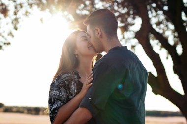 Genç çift kırsalda güzel ve güneşli bir günün tadını çıkarıyor. Öpüşüyorlar, sarılıyorlar, birlikte olmaktan mutlular.