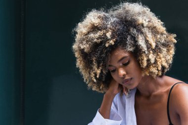 Düşünceli Afrikalı Amerikalı kadın şık giyinmiş renkli kapıya bakarken aşağıya bakıyor.