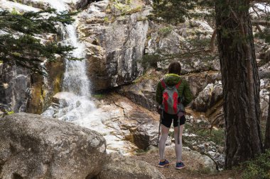 Anonim gezgin kadının kaya üzerinde dikilip Pireneler 'deki görkemli şelalenin manzarasına baktığı arka plan.