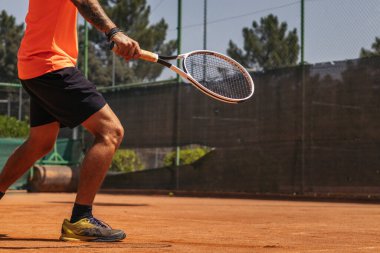 Spor giyim kuşağında, kirli tenis kortunda tenis oynayan tanınmamış bir adamı yakından çek..