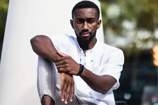 stock image Confident African American male in summer outfit relaxing on concrete bench in city on sunny day