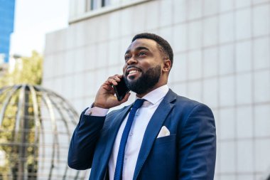 Takım elbiseli iş adamı ofisten çıkarken telefonda konuşuyor.