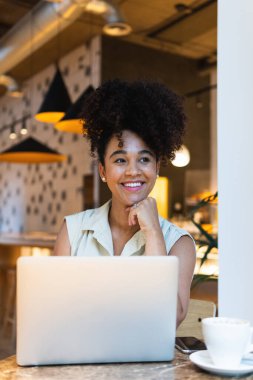 İnternette yazı yazan kıvırcık saçlı Afro-Amerikan kadın.