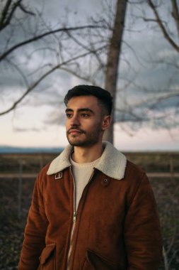 Doğada kahverengi ceketli çekici bir adamın portresi.