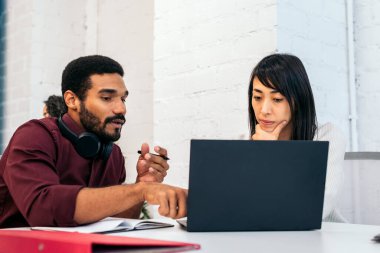Şirket toplantısındaki iş arkadaşları şirket verilerini analiz ediyorlar. Modern bir ofis alanının toplantı odasındalar.
