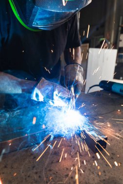 Tanımlanamayan, koruyucu kask takan, atölyedeki tezgahta metal kaynak yapan erkek bir usta.