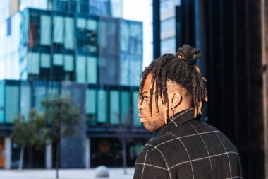 Görünüşü bulanık şehir manzarasında çörekleri olan Afrikalı Amerikalı bir adam başka tarafa bakıyor.