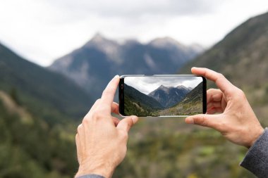 Pireneler 'in dağ sıralarının fotoğrafını çeken tanınmayan ekin kâşifi yürüyüş sırasında cep telefonuyla konuşuyor.