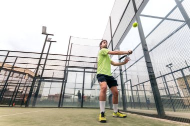 Genç adam raket tenisi oynuyor. düşük açı