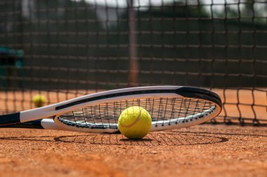 Toprak sahada tenis topuyla raketin yakın çekimi. İmaj spor ve sağlıklı yaşam kavramını ifade ediyor..