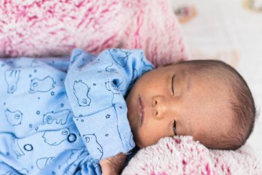 Yukardan gelen huzurlu, tapılası yeni doğmuş bebek büyük bir oyuncağın üzerinde, battaniyenin üzerinde yatıyor.