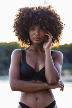 Sakin siyah kadın bikini giyiyor yazın sakin deniz suyunda duruyor ve başka tarafa bakıyor.