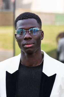 Şık ceketli genç, kendine güvenen siyahi girişimci şehirde kameraya bakıyor.