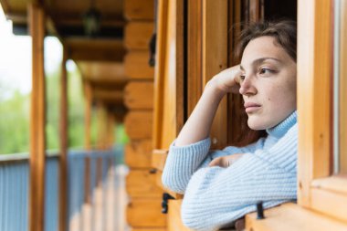 Pyrenees sıradağlarına bakarken pencerelere dayanan ahşap kulübelerin terasında dinlenen huzurlu kadın gezginin yan görüntüsü