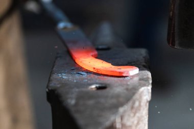 Eldivenli anonim zanaatkarlar demirci atölyesinde çekli sıcak metal parçaları yapıyorlar.