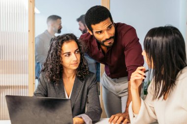 Şirket toplantısındaki iş arkadaşları şirket verilerini analiz ediyorlar. Modern bir ofis alanının toplantı odasındalar.