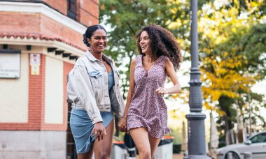 Lezbiyen çift yaya geçidinde koşuyor. Neşeli bir şekilde gülüyorlar..