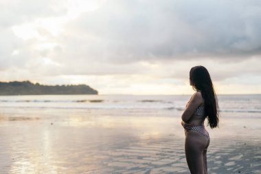 Gün batımında denizin önündeki kadın.