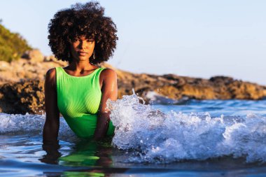 Güzel, baştan çıkarıcı, mayo giymiş ve yaz tatili boyunca denizde kıvırcık saçlı Afro-Amerikan kadın.