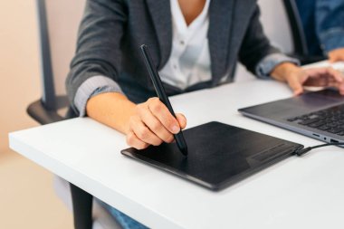 Ofiste grafik tableti kullanan tanınmayan bir kadının yakın plan fotoğrafı.