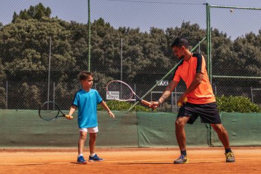 Teniste bir çocuğu eğiten, ona hareketler ve duruşlar öğreten bir adam. Böylece çocuk en iyisidir..