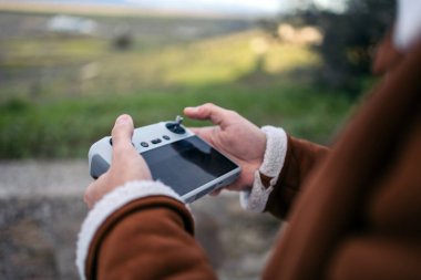 İnsansız hava aracını çalıştırırken bir pilotun elinde bir ekran tutarken yakın plan görüntüsü..