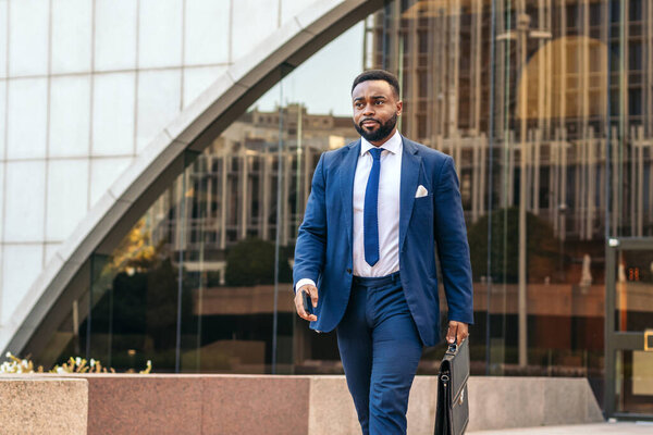 Business black man in suit leaving the office holding his work briefcase