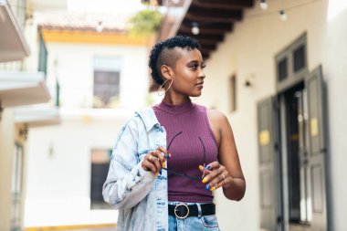 Kısa kıvırcık saçlı ve büyük küpeli havalı bir Afro-Amerikan kadının portresi