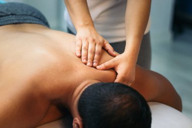 Genç bir kadın erkek bir hastayı tedavi ediyor. Sırt masajı fizyoterapisi. yakın plan