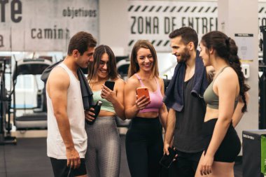 Spor salonunda konuşan ve cep telefonu kullanan arkadaşlar.