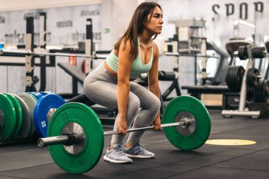 Spor salonunda kaldırma yapan kadın sporcu. yan görünüm