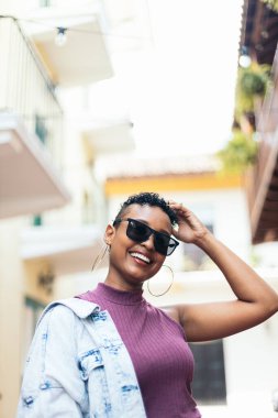 Kısa kıvırcık saçlı ve büyük küpeli havalı bir Afro-Amerikan kadının portresi